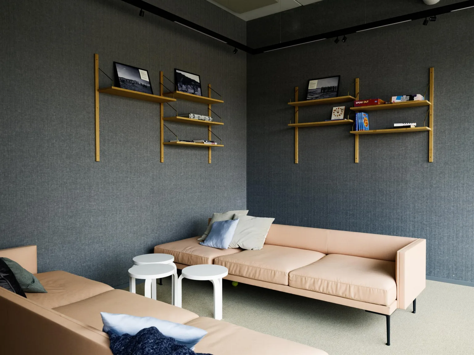 5. Ett mysigt loungeområde med rosa soffor, små runda bord, hyllor på väggen och dekorativa kuddar.
