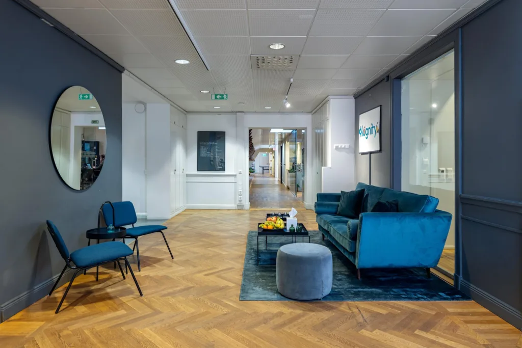 3. Ett loungeområde med blå soffa, stolar, soffbord och parkettgolv.