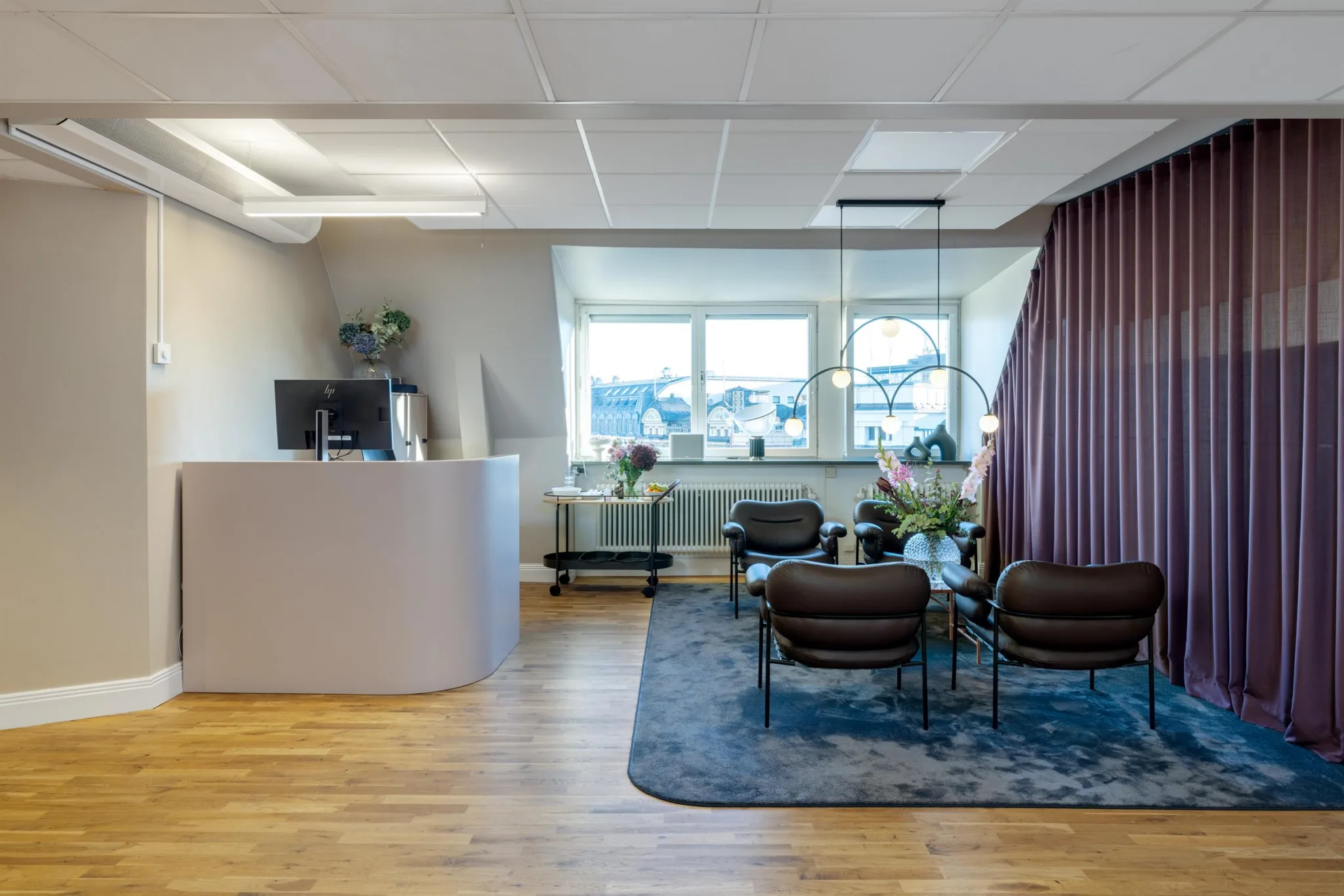 Ett modernt väntrum med reception, sittgrupp och stora fönster som släpper in ljus.