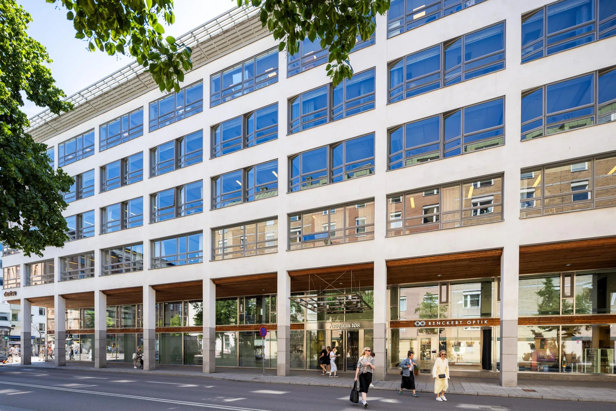 En modern byggnad med stora glasfönster och människor som går på trottoaren.