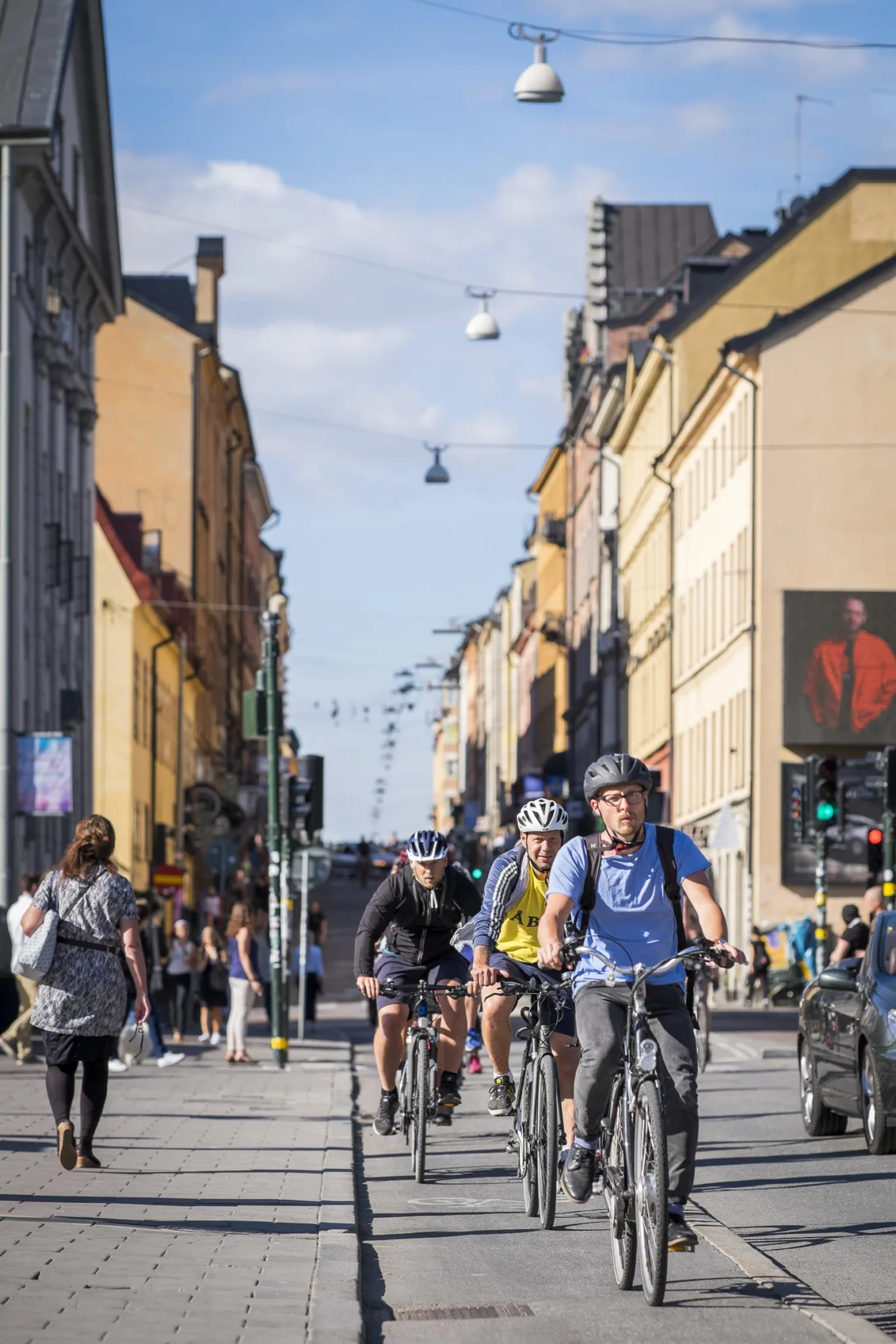 Cykeltrafik på en stadsgata med omgivande byggnader under en solig dag.