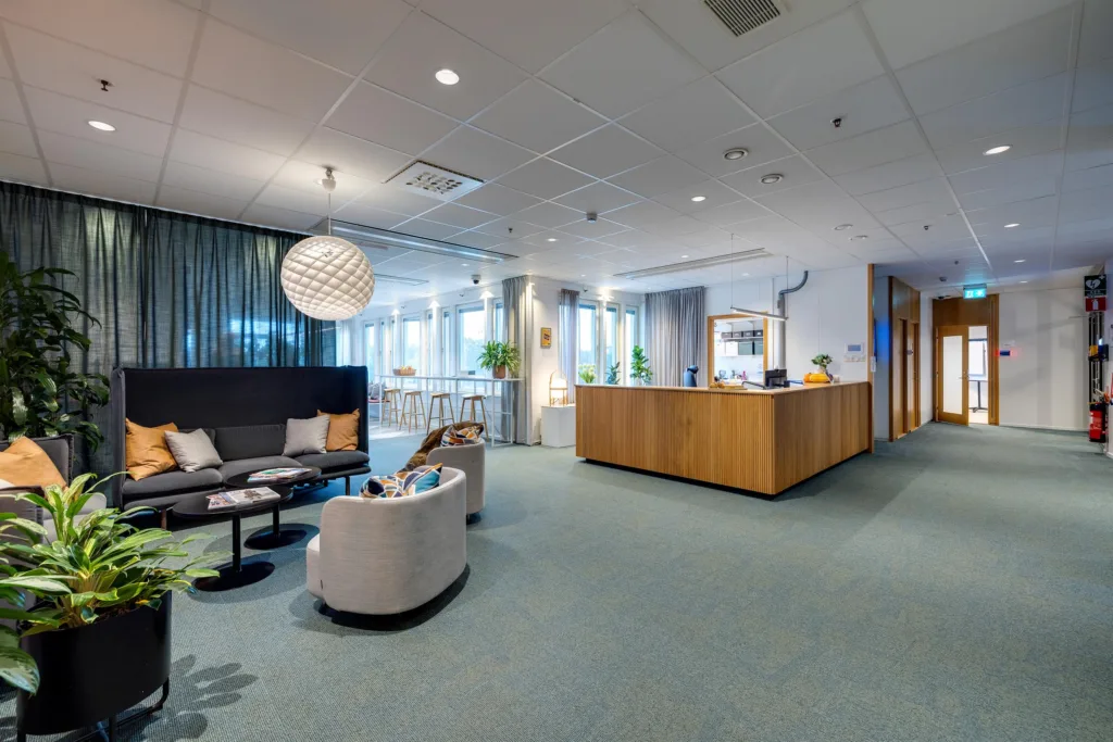5. En reception med en trädisk, sittgrupp med soffor och bord, samt dekorativa element som en stor lampa och växter.