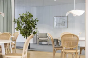 5. Ett kontorsrum med trämöbler, en grön växt och glasväggar som delar av utrymmet.