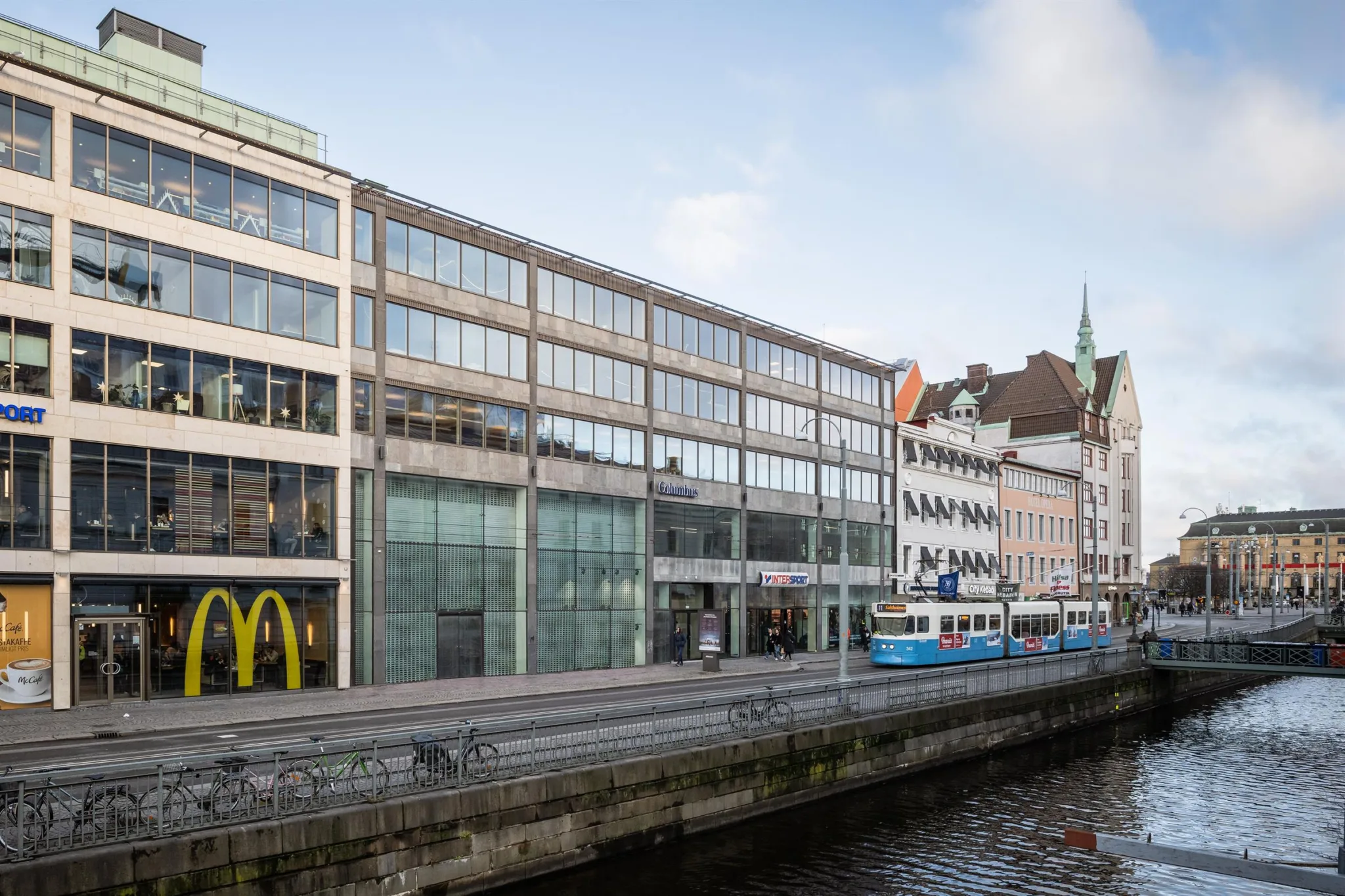 1. En byggnad med glasfasad vid en kanal, där McDonald's och spårvagnsskyltar syns.