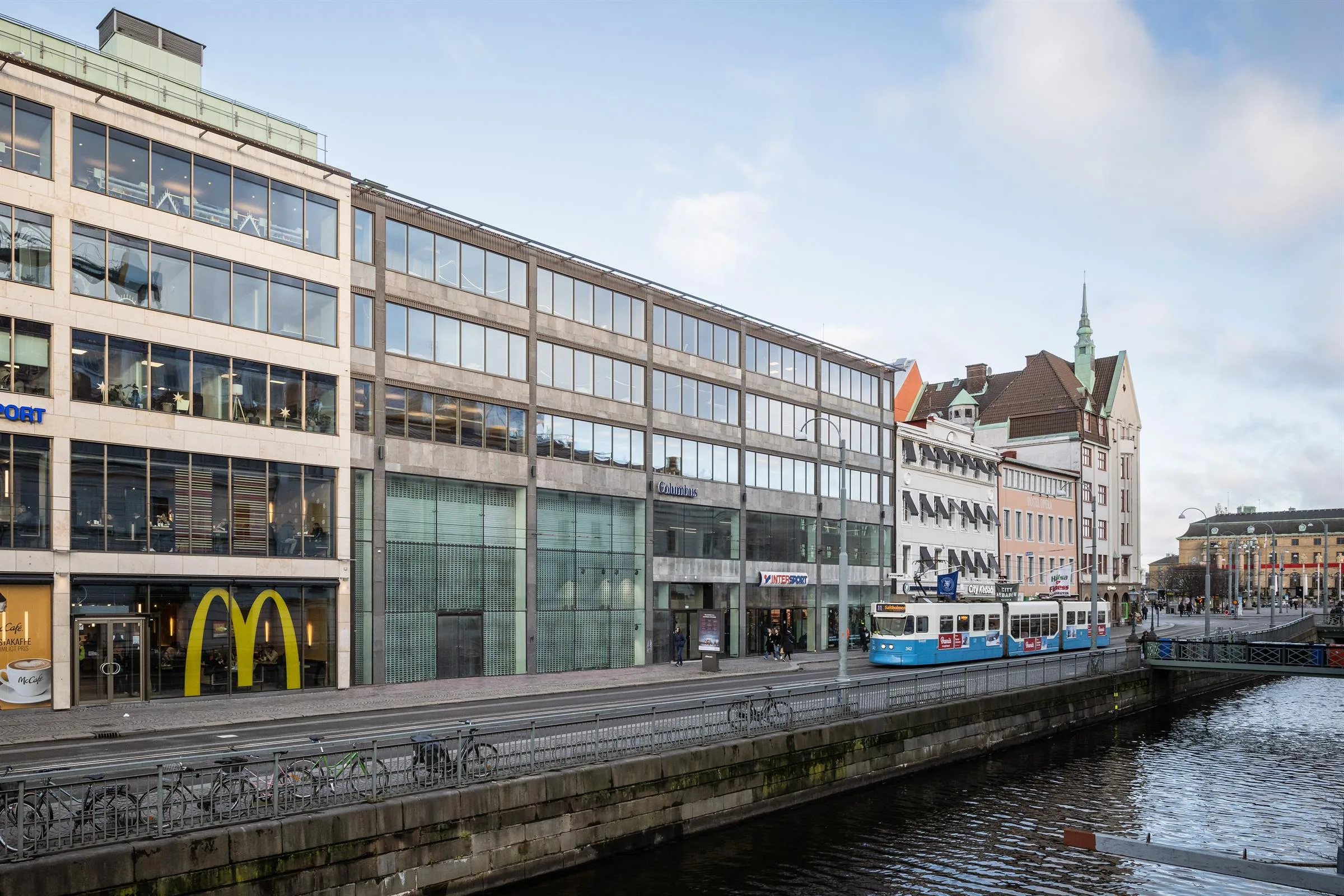 1. En byggnad med glasfasad vid en kanal, där McDonald's och spårvagnsskyltar syns.