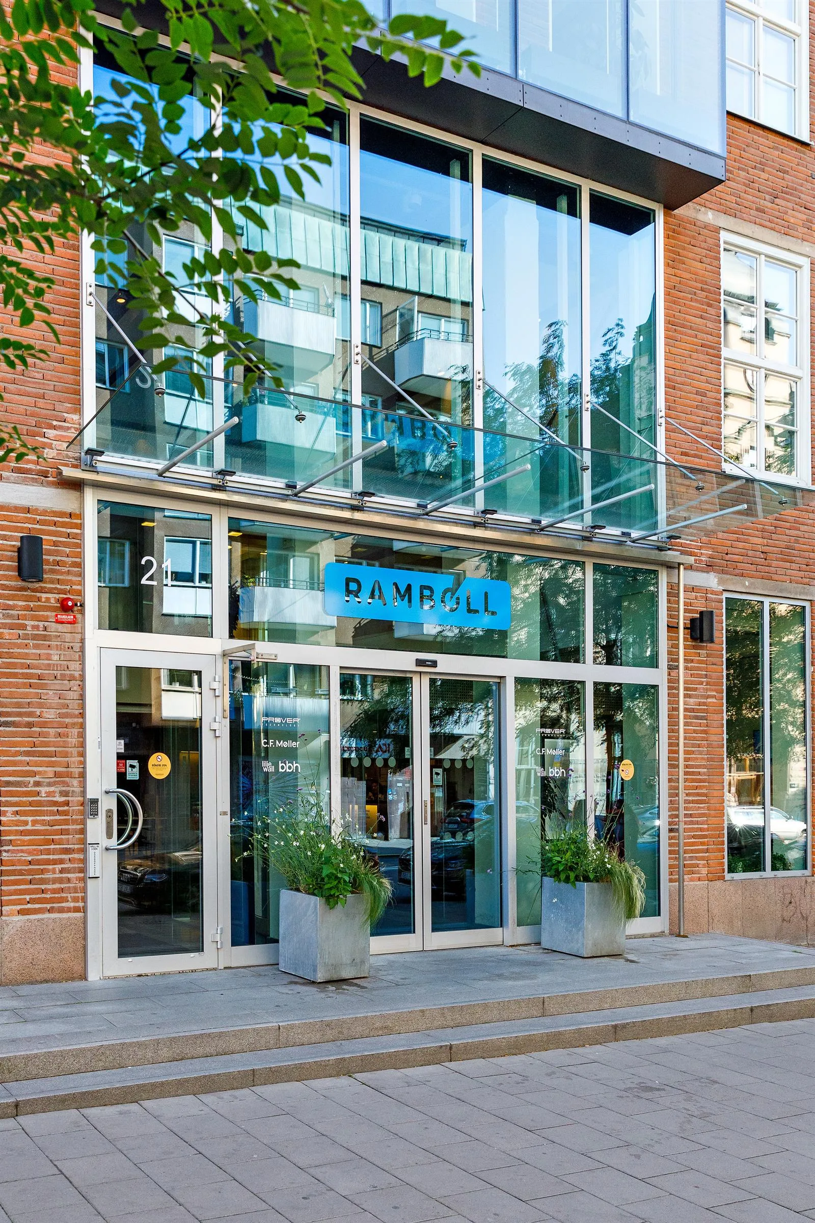 Entré till en byggnad med glasdörrar, stora fönster och skylten "DAMPALL".