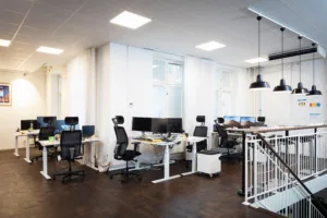 4. Ett öppet kontorslandskap med höj- och sänkbara skrivbord, kontorsstolar och datorskärmar.
