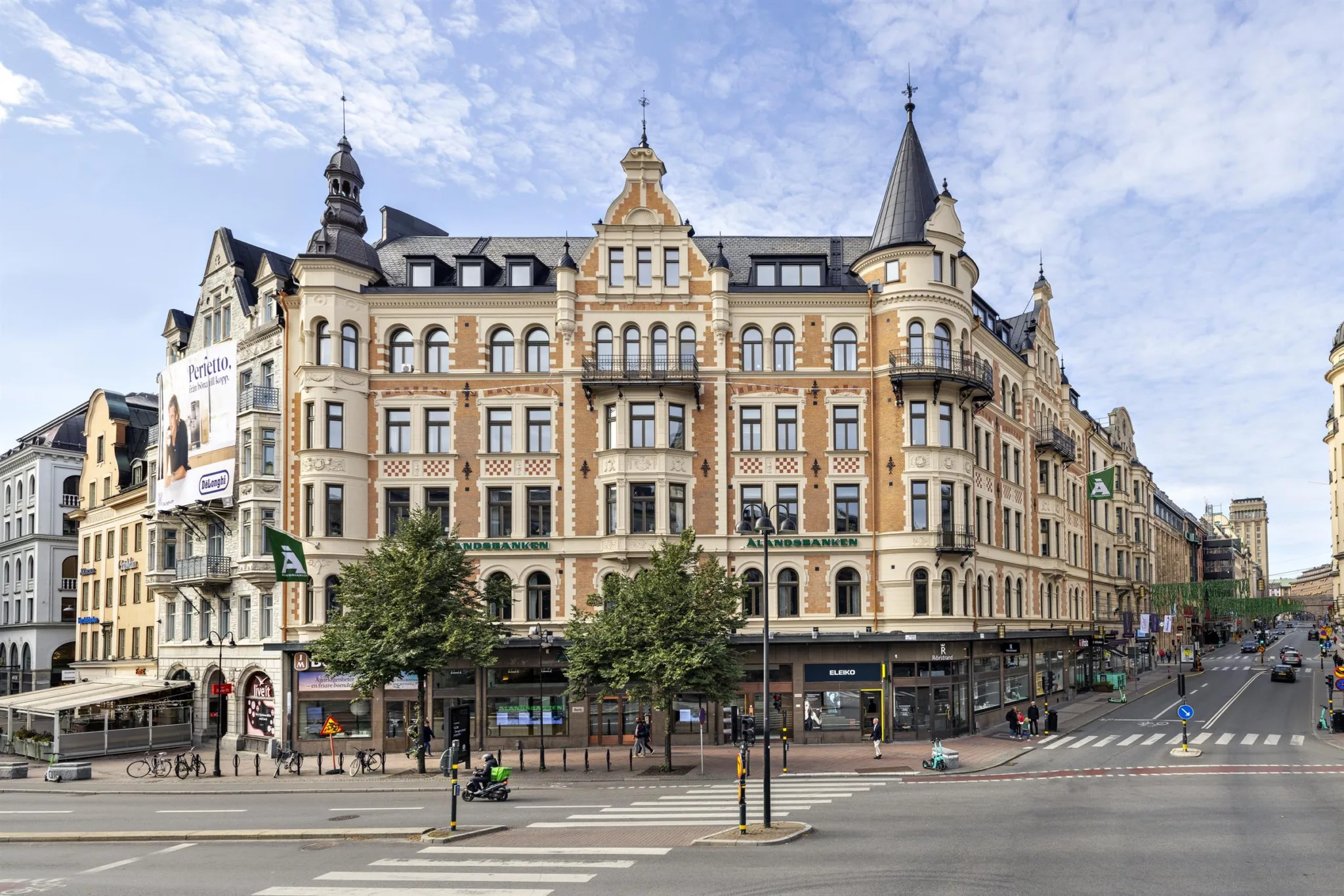 En stor byggnad med detaljerad arkitektur, flera våningar och butiker på bottenvåningen.