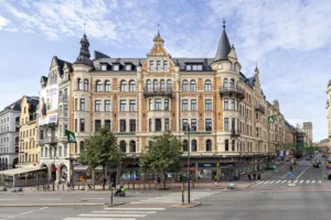En stor byggnad med detaljerad arkitektur, flera våningar och butiker på bottenvåningen.