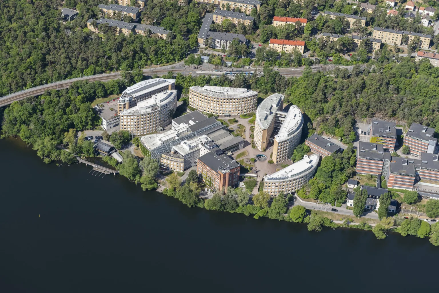 2. Flygbild av en kontorsanläggning med flera runda byggnader omgivna av skog och vatten.