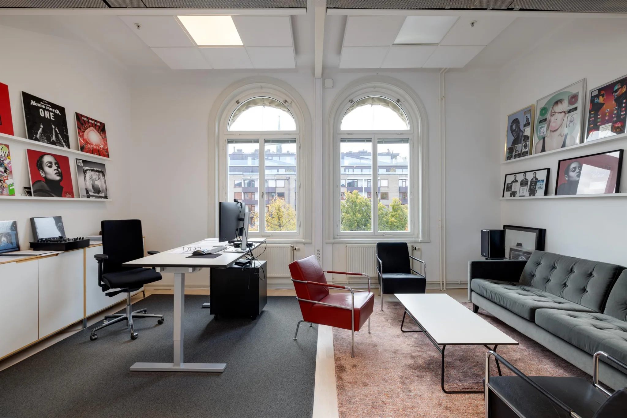 4. Ett kontor med två stora bågformade fönster, skrivbord, röd fåtölj och soffgrupp.
