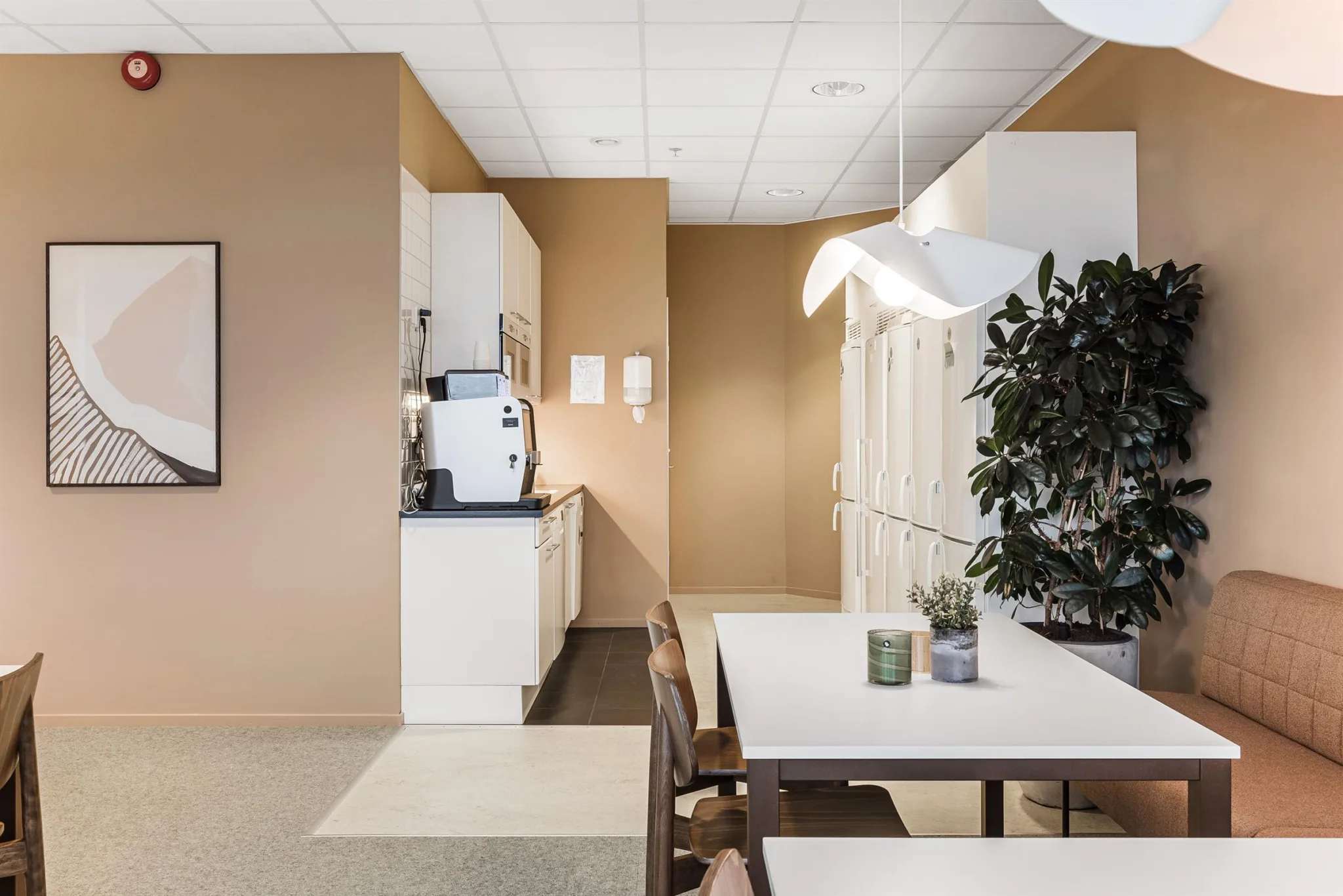 1. Ett kök med vita skåp, kaffemaskin, matbord och stolar samt en hängande lampa.