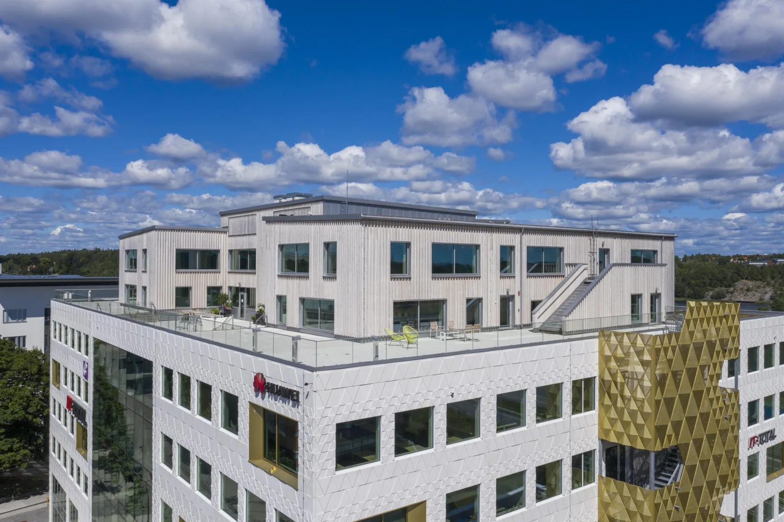 En modern byggnad med vita fasader under en klarblå himmel med moln.