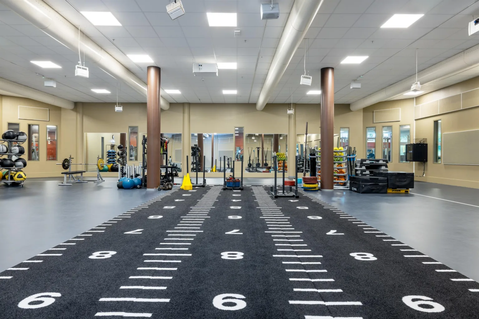 1. Ett gym med en svart träningsmatta markerad med siffror och träningsutrustning i bakgrunden.