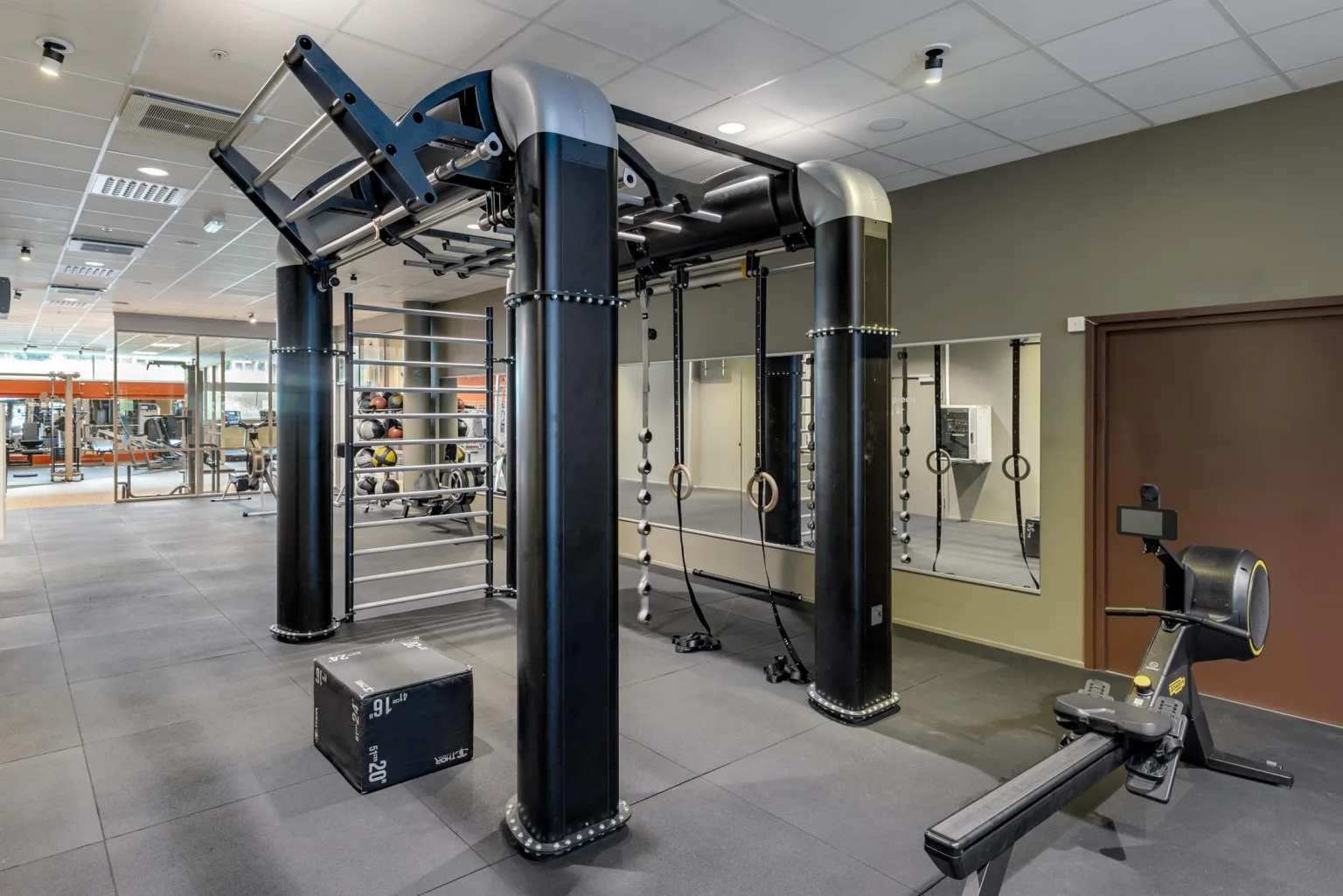 2. Ett gym med en multifunktionell träningsmaskin, speglar och träningsutrustning.