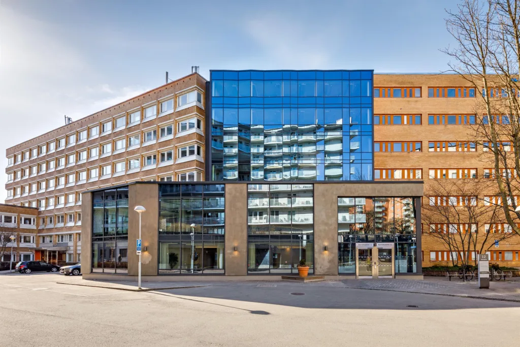 En byggnad med blandad arkitektur, inklusive glasfasad och tegel, belägen vid en stadsgata.