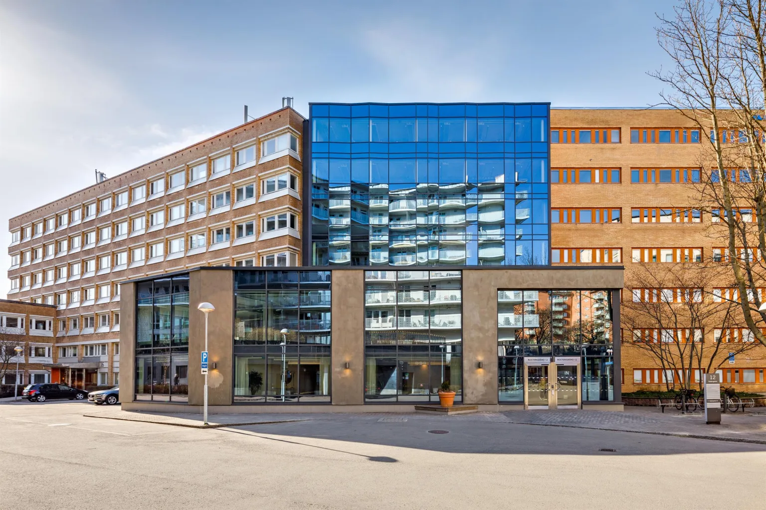 En byggnad med blandad arkitektur, inklusive glasfasad och tegel, belägen vid en stadsgata.