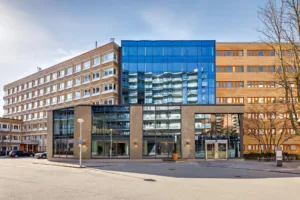 En byggnad med blandad arkitektur, inklusive glasfasad och tegel, belägen vid en stadsgata.
