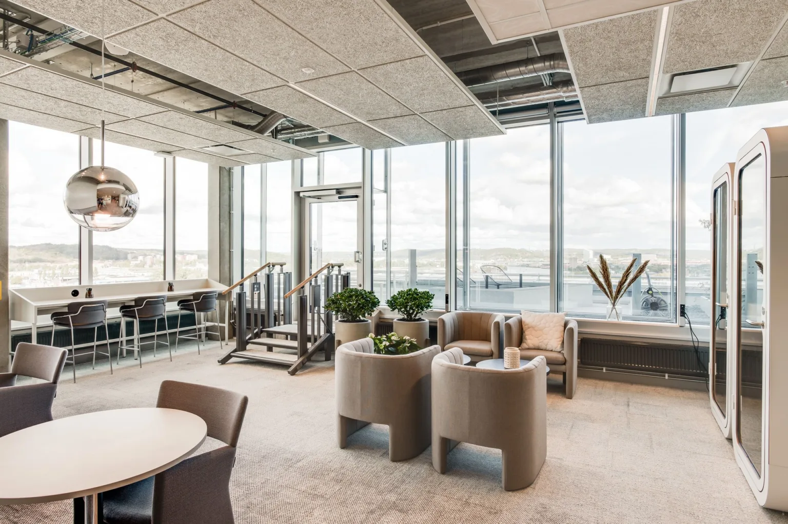 4. En ljus och rymlig lounge med utsikt över natur och vatten, möbler och växter.