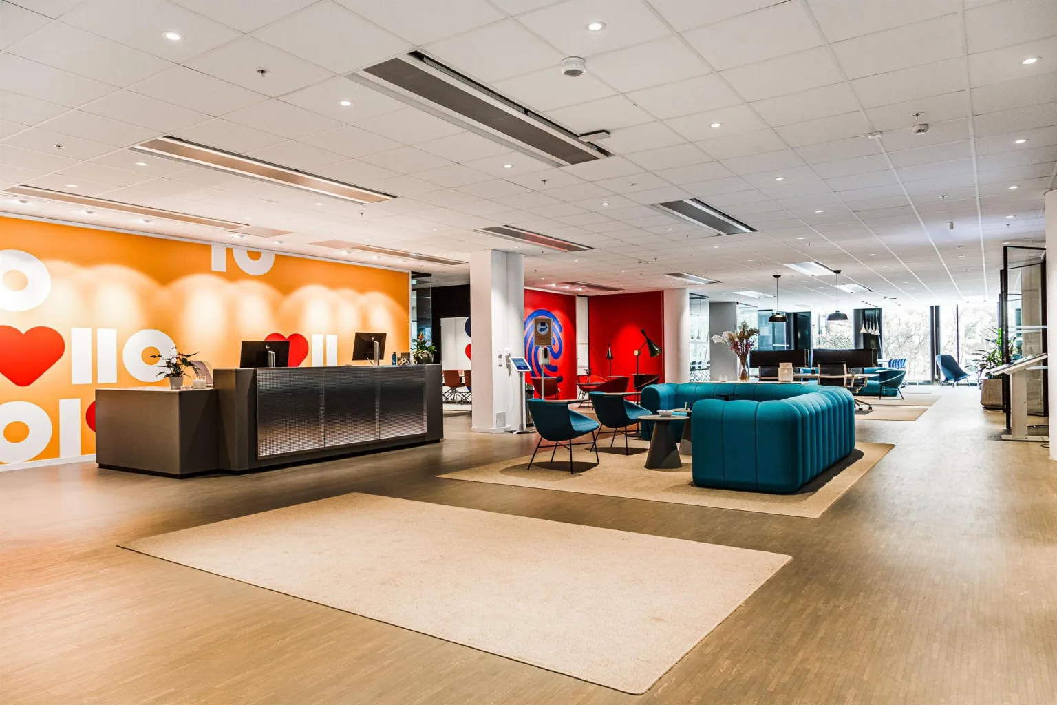 1. Reception med orange bakgrund, soffgrupper och färgglada väggar i en modern kontorsmiljö.