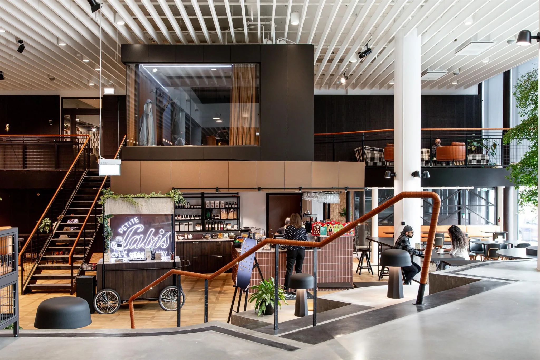 Ett modernt kafé med trämöbler, stora fönster och en våning ovanför.