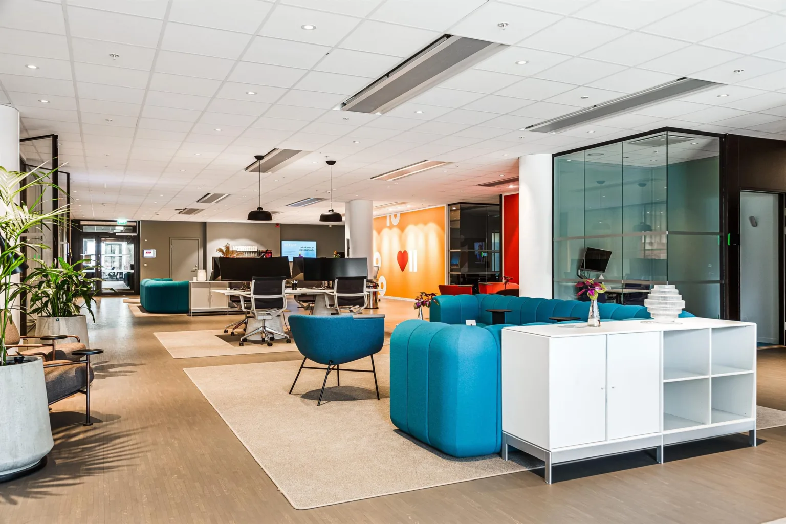 4. Ett flexibelt arbetsutrymme med blå sittmöbler, skrivbord och en ljus, modern inredning.