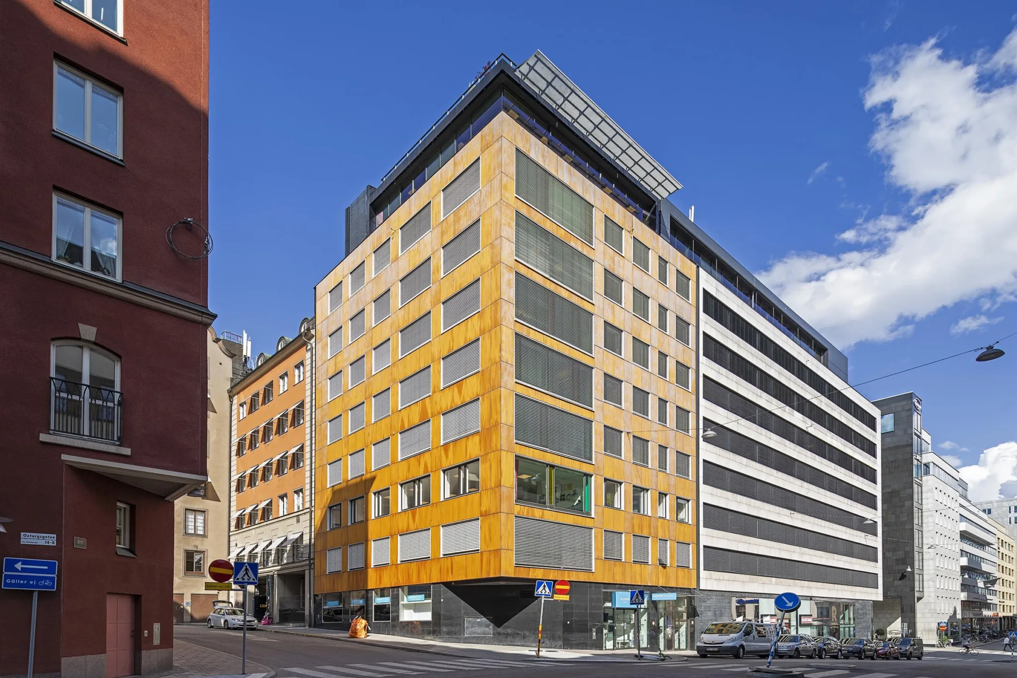 4. En modern byggnad med gula fasader och stora fönster, omgiven av andra byggnader.