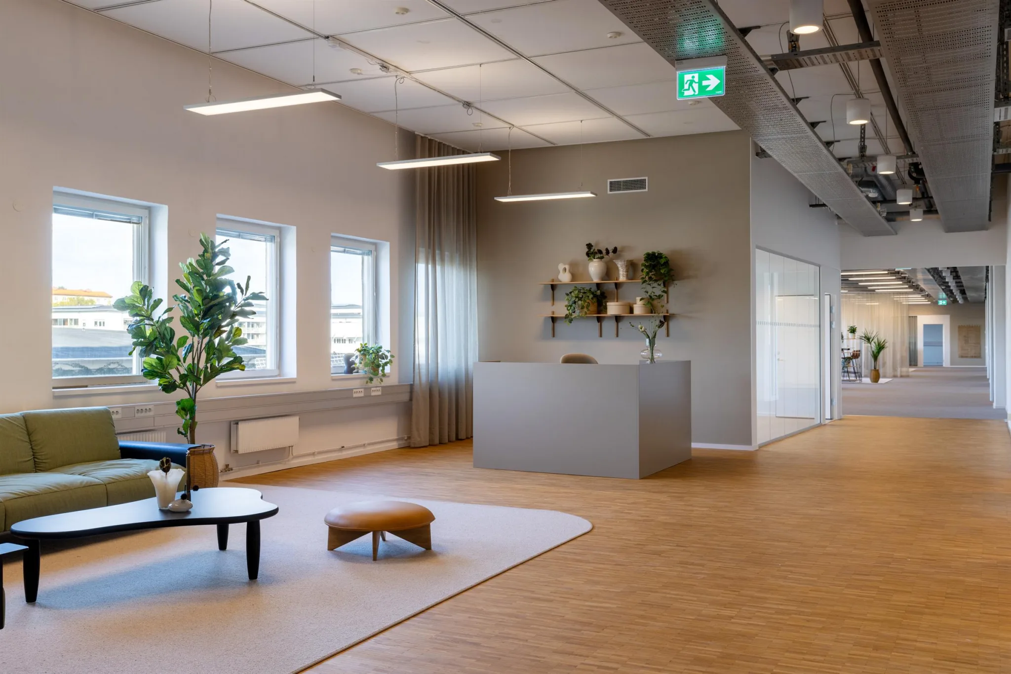 Ett modernt kontorsområde med reception, växter, soffor och trädetaljer.
