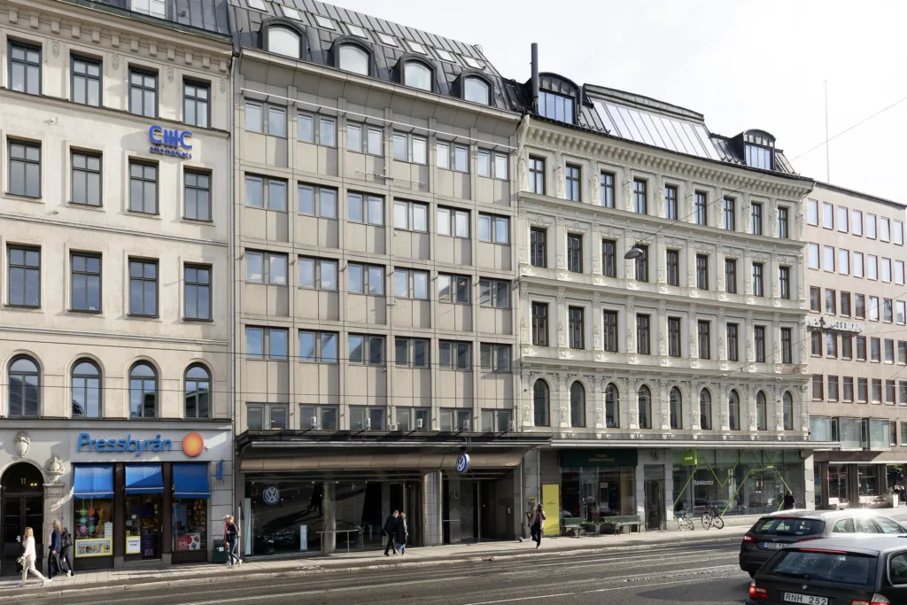 En fasad med flera våningar, stora fönster och olika butiker på bottenvåningen.