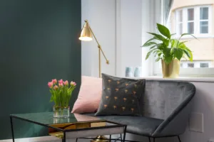 2. Ett vardagsrum med en grå soffa, färgglada kuddar, en guldlampa och en vas med rosa tulpaner.