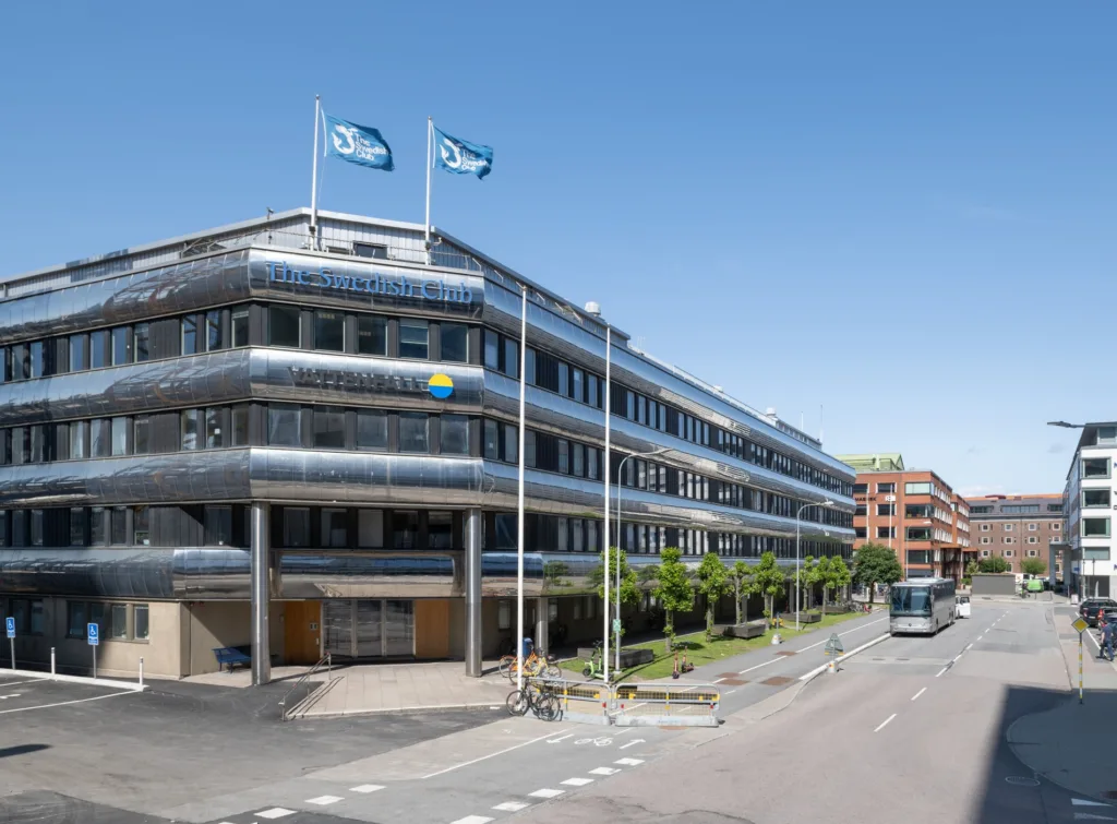 5. En kontorsbyggnad med rundade fasader, svenska flaggan och två blå flaggor på taket.
