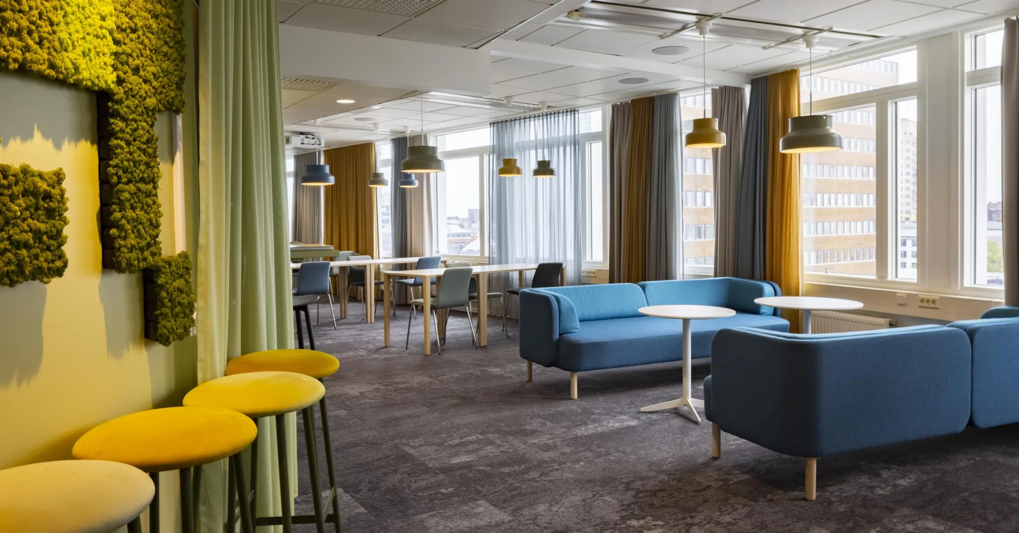2. Ett modernt caféutrymme med blå soffor, gula barstolar och hängande lampor.