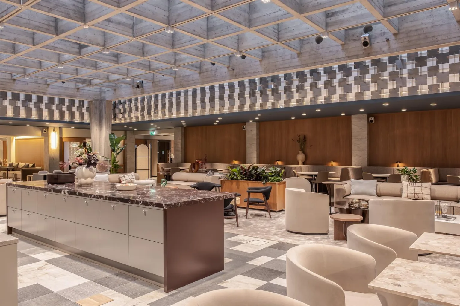 En rymlig lounge med moderna möbler, marmorbord och ett rutnätsmönstrat tak.