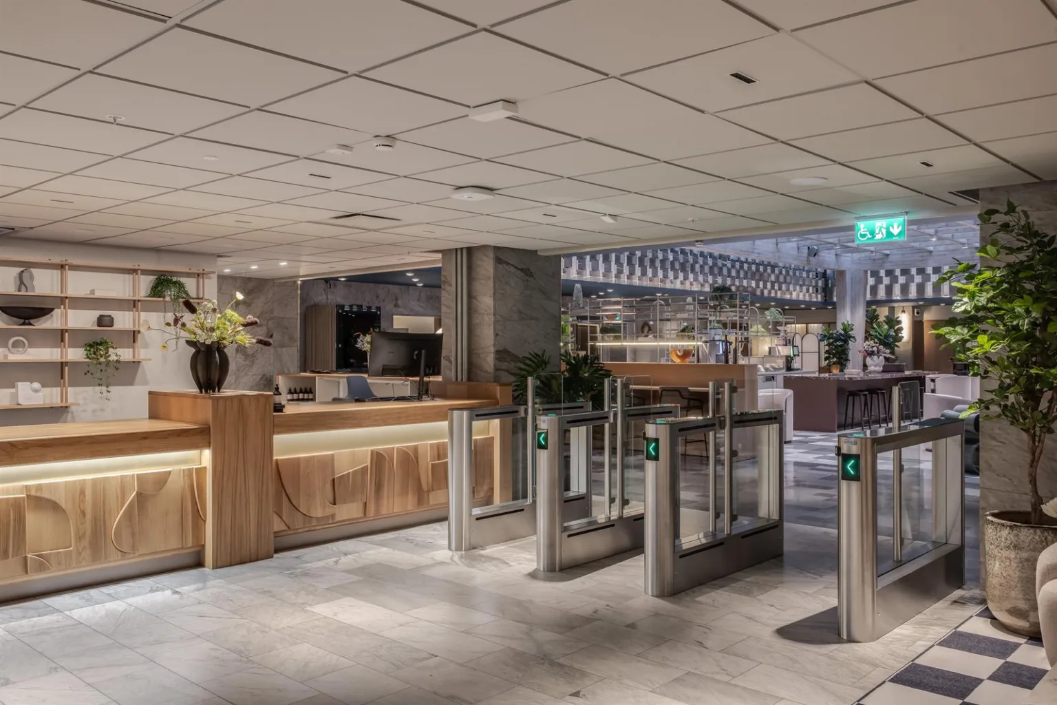 En reception med träpaneler och säkerhetsspärrar, omgiven av modern inredning och blommor.
